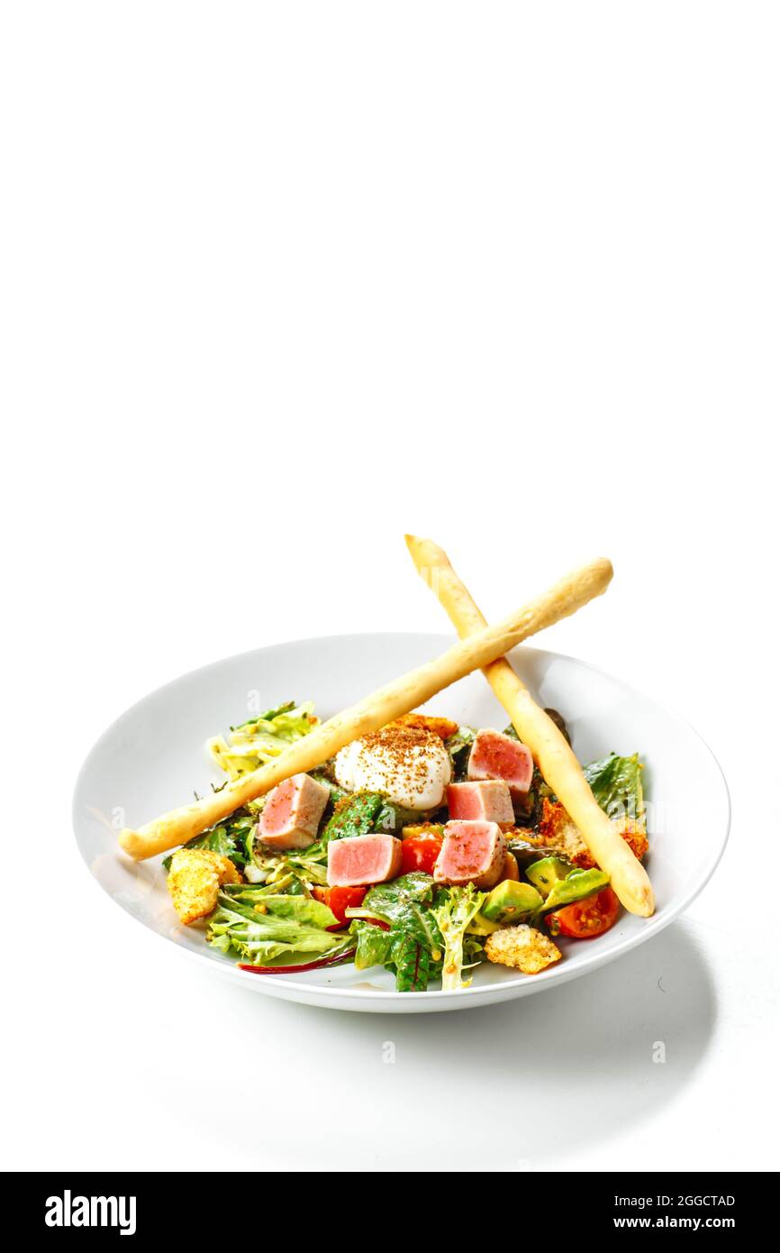 Plate with all tuna salad, cherry tomatoes, cheese and vegetables, served with breadsticks, isolated on white background, copy space. Stock Photo