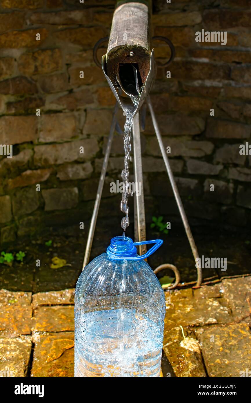 stream of water from a spring with splashes pours into a bottle Stock Photo