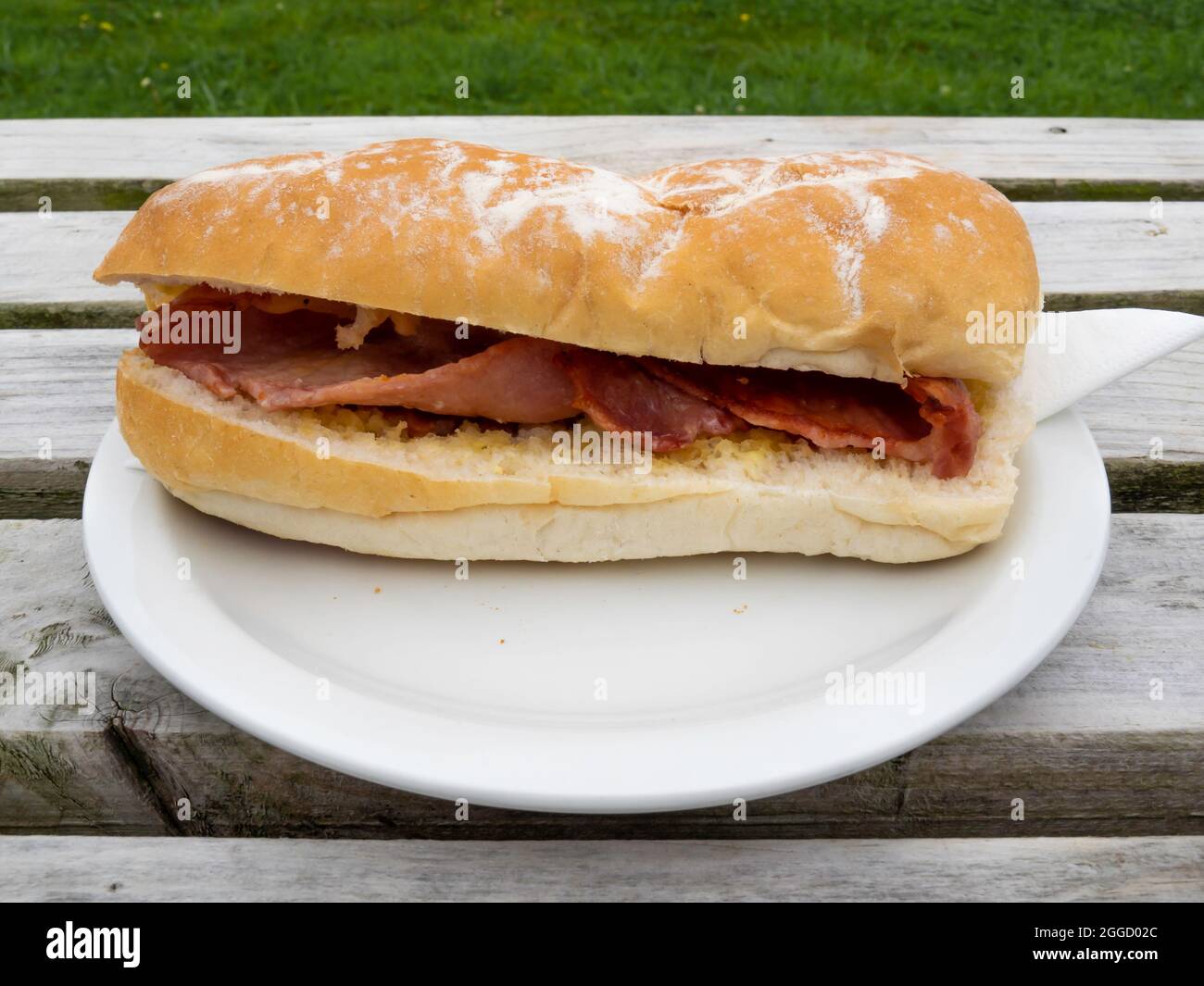 Lunchtime snack on an outside table Bacon in a soft white Roll Stock Photo