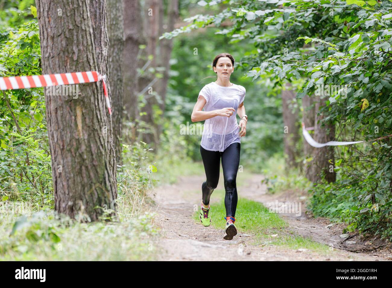 Young wet sportswoman running on her course in obstacle race after crossing a river Stock Photo