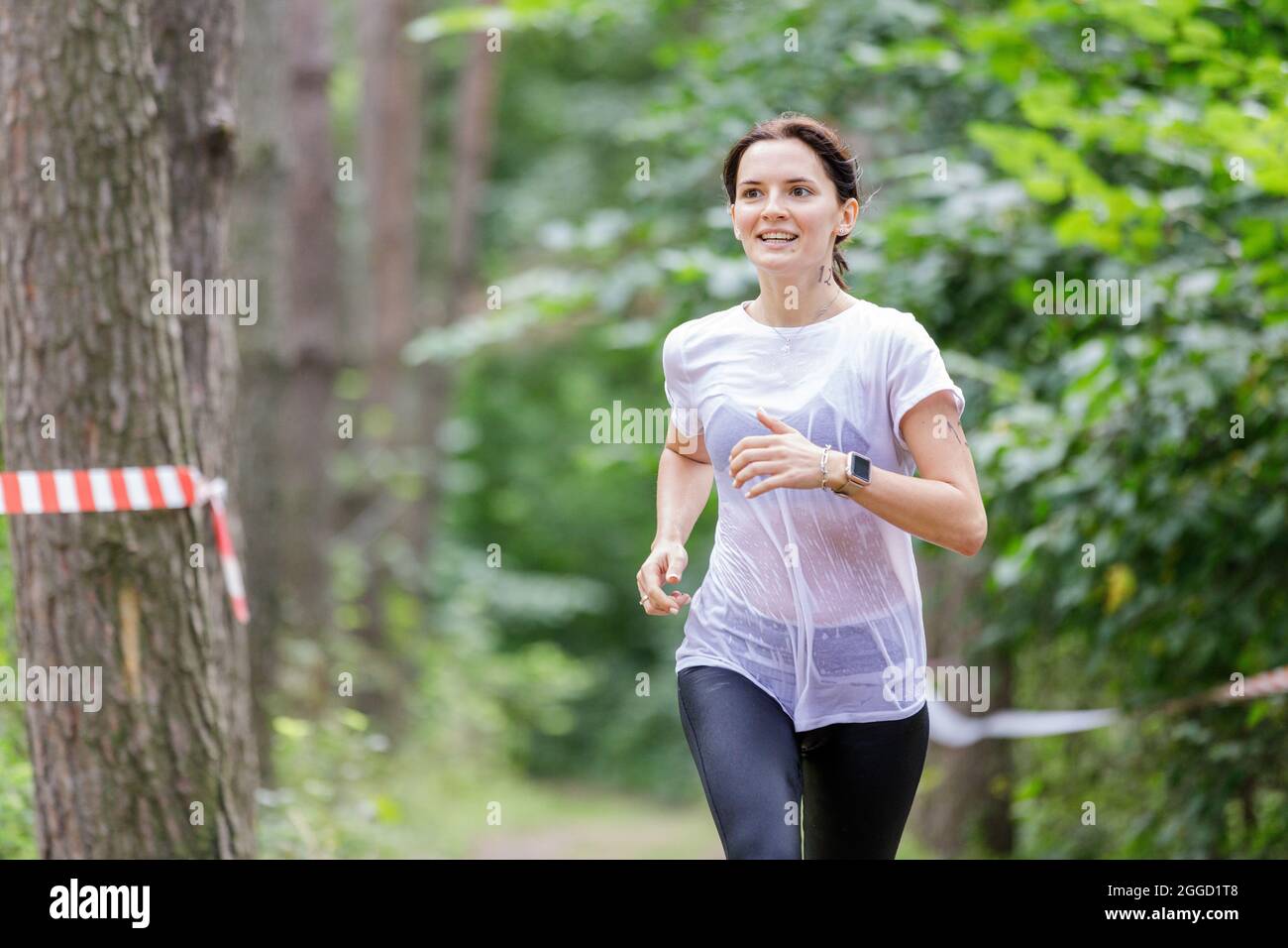 Young wet sportswoman running on her course in obstacle race after crossing a river Stock Photo
