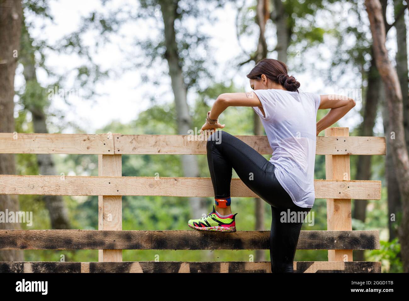 Young sportswoman climbing timber wall on her obstacle race course Stock Photo