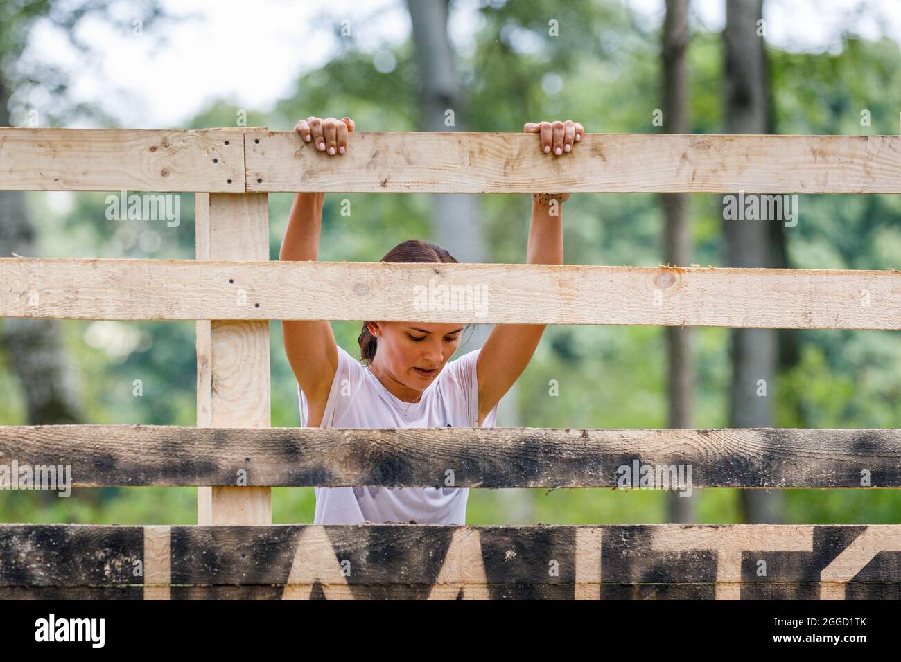 Young sportswoman climbing timber wall on her obstacle race course Stock Photo