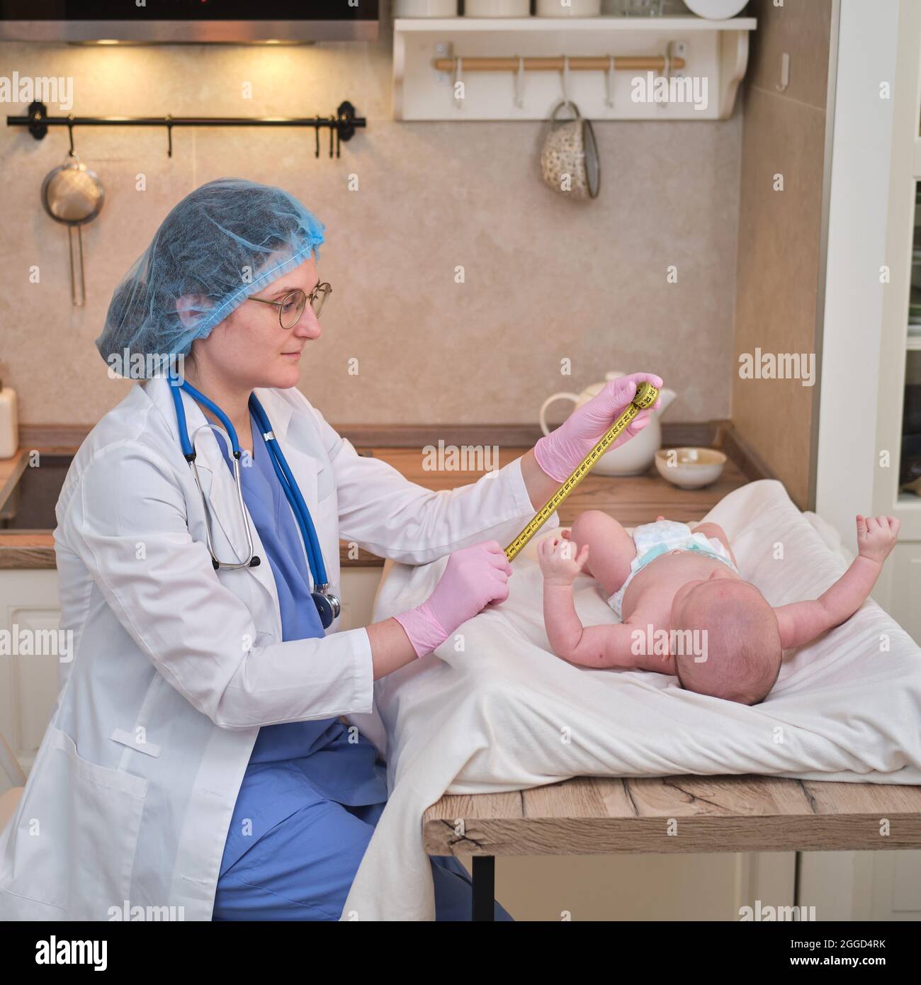 Doctor measures the growth of a newborn baby. A nurse in uniform checks the girth of the child head and abdomen Stock Photo