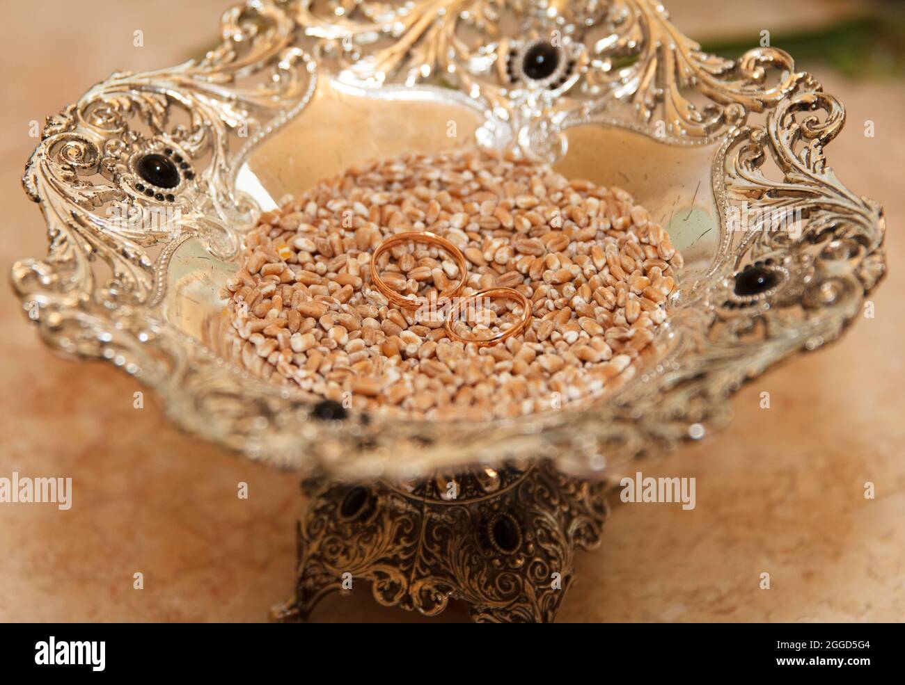 Wedding rings lie on a dish with wheat, a tradition among newly married