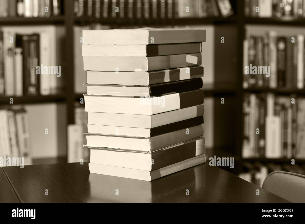 A stack of different books in a large library selected by the reader lies on table. black - white photo. Stock Photo