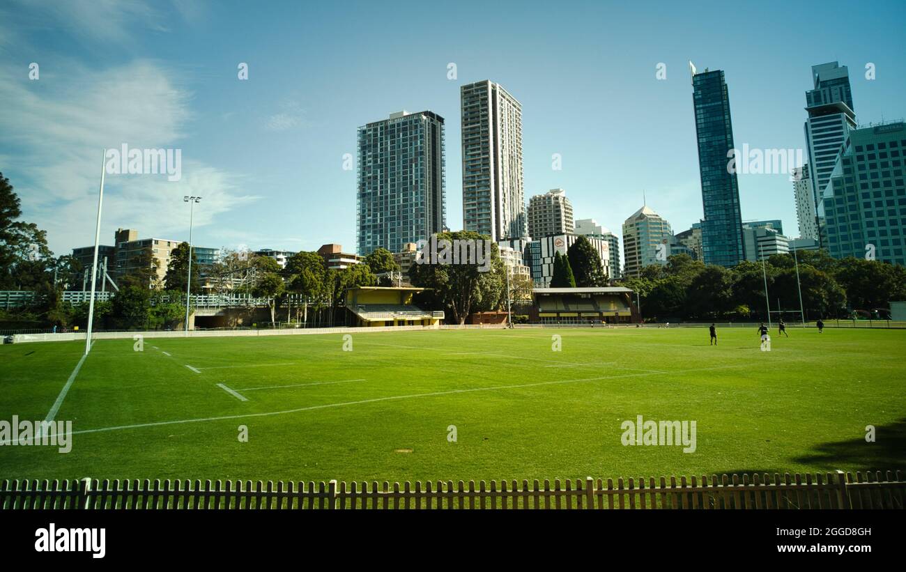 SYDNEY, AUSTRALIA - Apr 24, 2021: The morning sun shines on the oval as early risers run and exercise against the backdrop of Chatswood skyscrapers Stock Photo