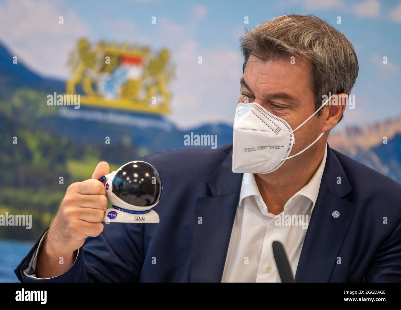 Munich, Germany. 31st Aug, 2021. Markus Söder (CSU), Prime Minister of Bavaria, looks at a new mug in the shape of an astronaut's helmet at the beginning of the first meeting of the Bavarian cabinet after the summer break. Among other things, the Council of Ministers wants to pass the new Corona Ordinance, which no longer makes requirements dependent on incidence alone and provides for the end of the FFP-2 mask requirement. Credit: Peter Kneffel/dpa/Alamy Live News Stock Photo