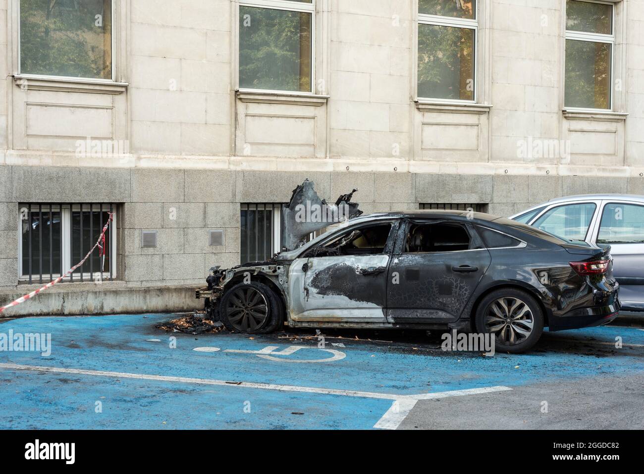 Burned out destroyed damaged car on disabled handicap parking space bay
