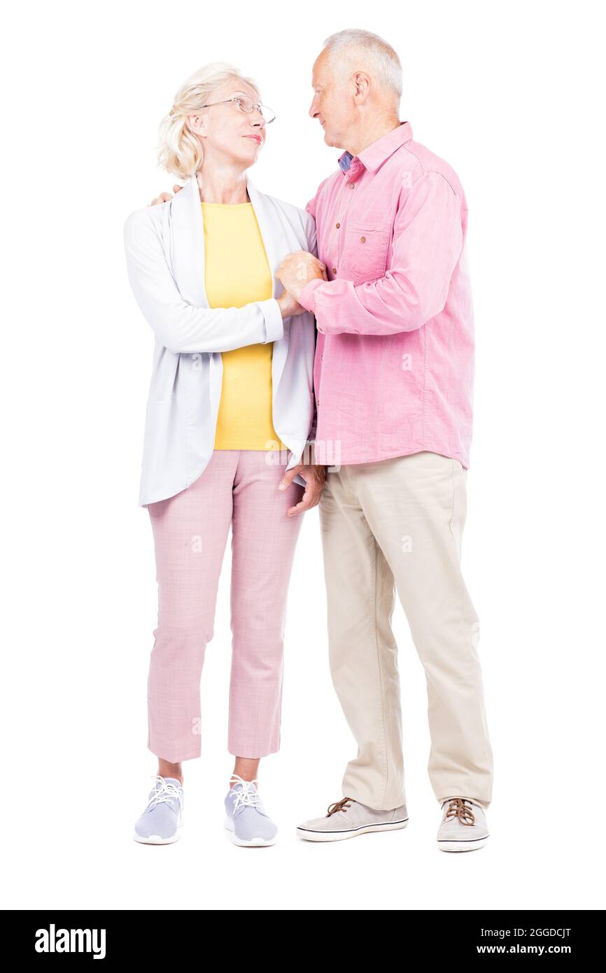 Vertical full length shot of of senior married man and woman standing together looking at each other Stock Photo