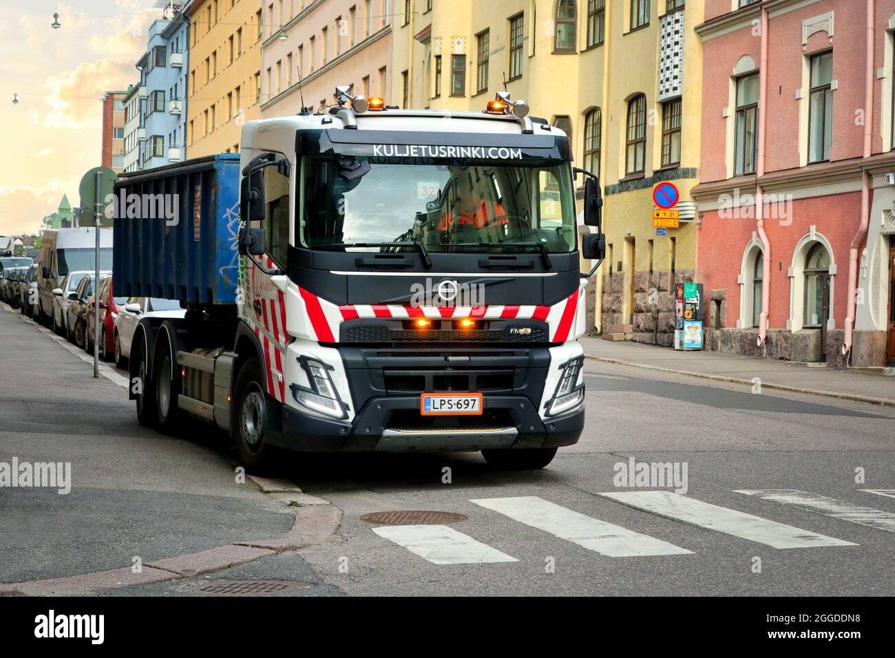 New Volvo FMX500 6x2 hooklift truck Kuljetusrinki Oy rolls on skip bin onto the back of the vehicle. Helsinki, Finland. August 2, 2021. Stock Photo