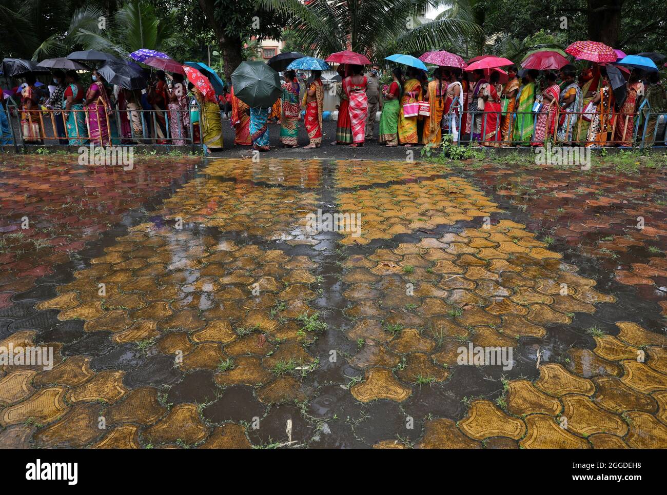 Women hold umbrellas to cover from rain as they wait to receive a dose of COVISHIELD vaccine, a coronavirus disease (COVID-19) vaccine manufactured by Serum Institute of India, outside a vaccination centre in Kolkata, India, August 31, 2021. REUTERS/Rupak De Chowdhuri Stock Photo