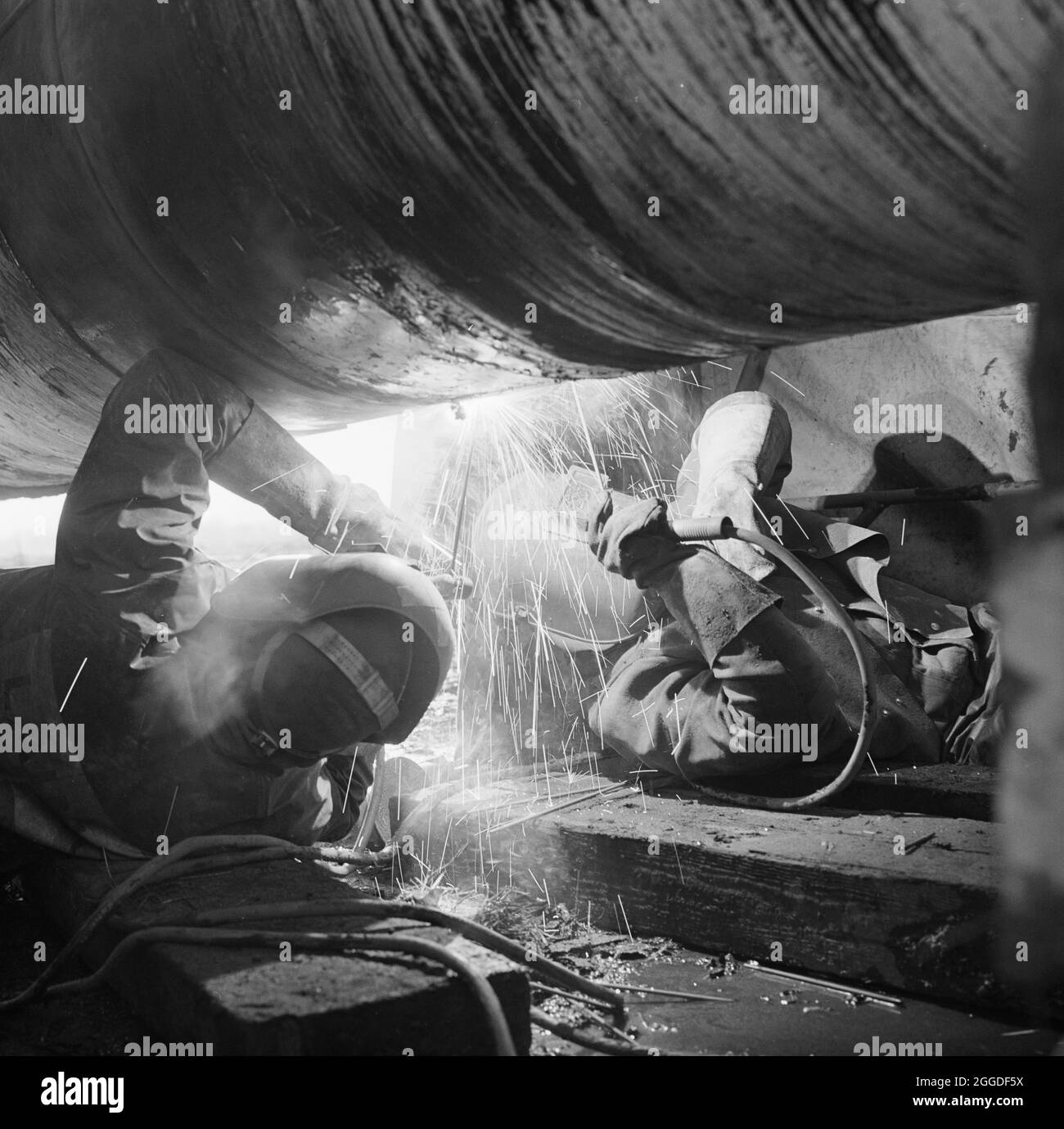 Two welders at work on the Rugby gas pipeline. This pipeline was part of a pipeline carrying North Sea natural gas from the Norfolk coast to the Rugby area where it was connected with an existing natural gas pipeline supplying eight of Britain's area gas boards. The work was carried out by Laing Civil Engineering along with French companies Entrepose and Grands Travaux de Marseille (GTM). Stock Photo