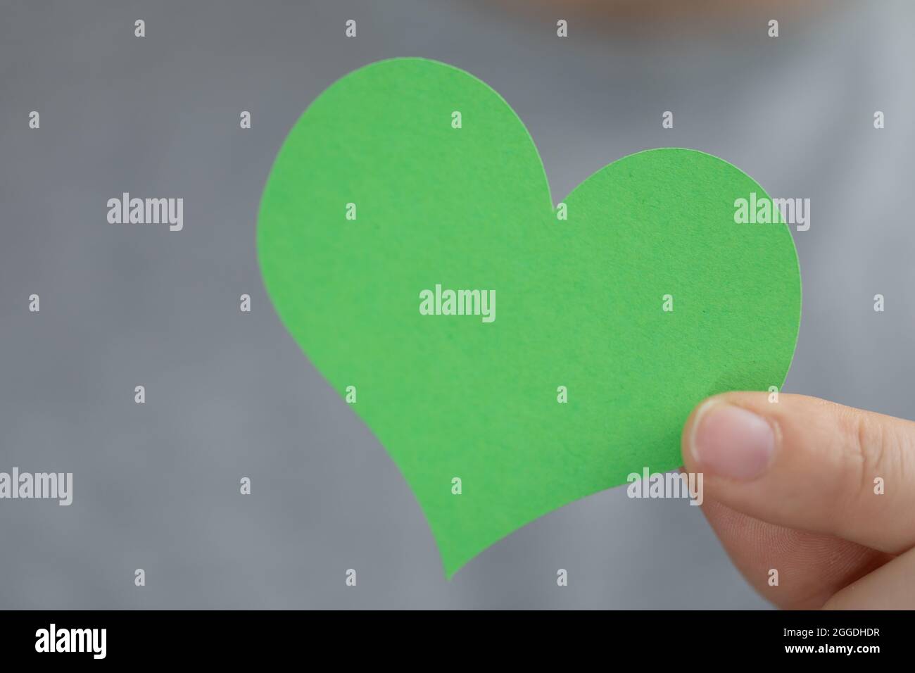 Closeup of a hand holding a green paper heart. Green power, future ...