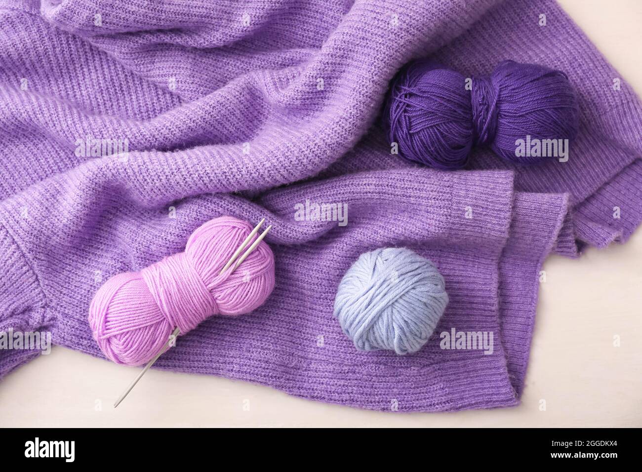 Yarn with knitting needles and sweater on white background Stock Photo ...