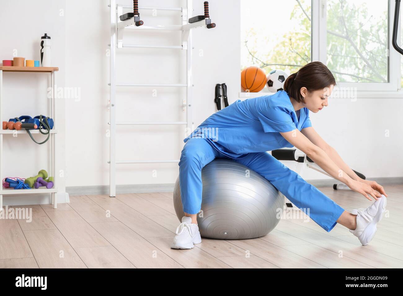 Female physiotherapist demonstrating exercise with fitball in