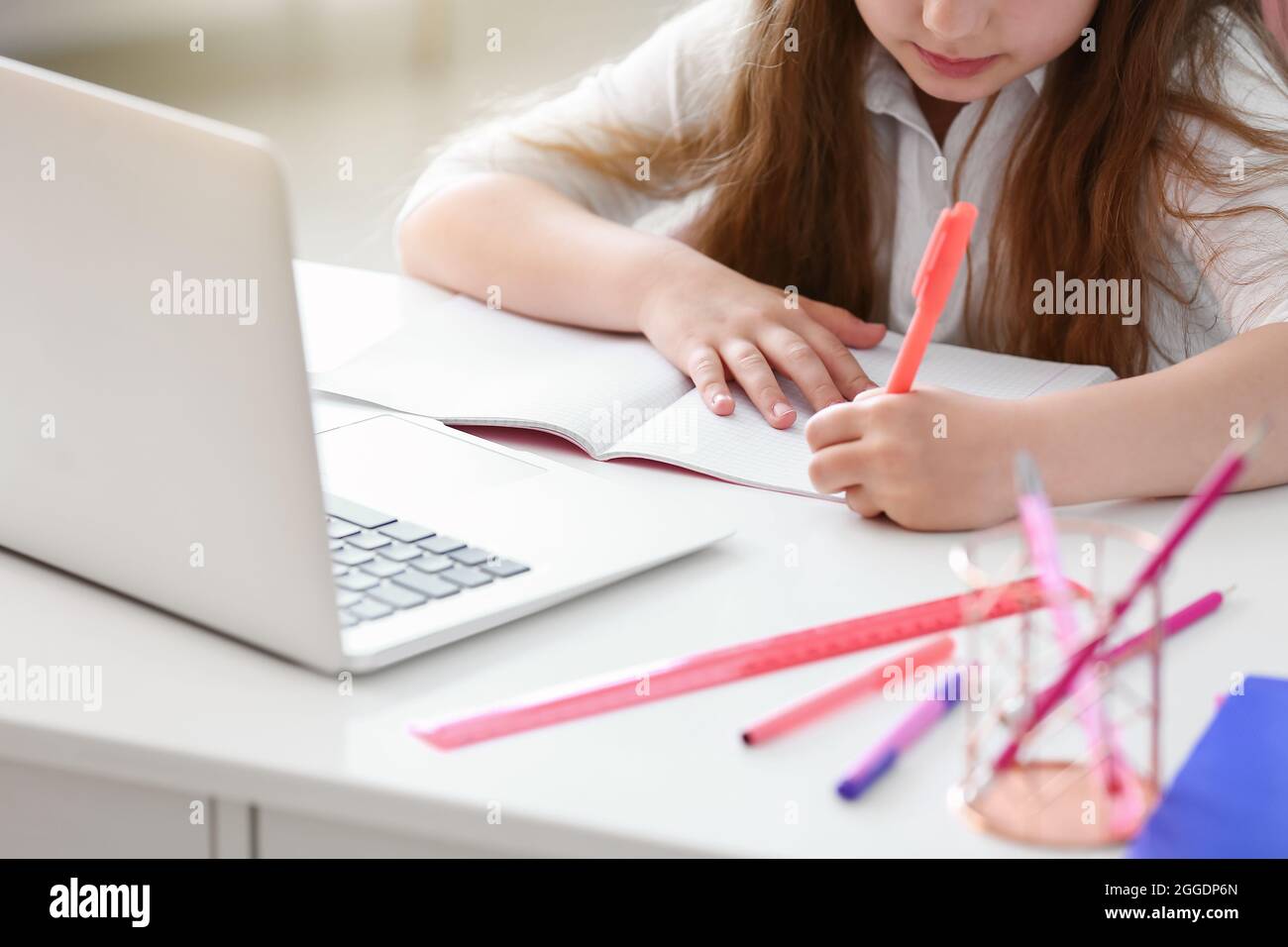 Little girl doing lessons online at home Stock Photo