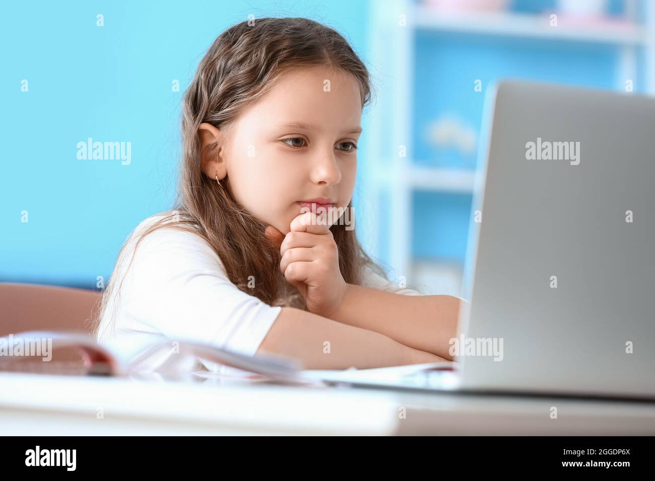 Little girl doing lessons online at home Stock Photo