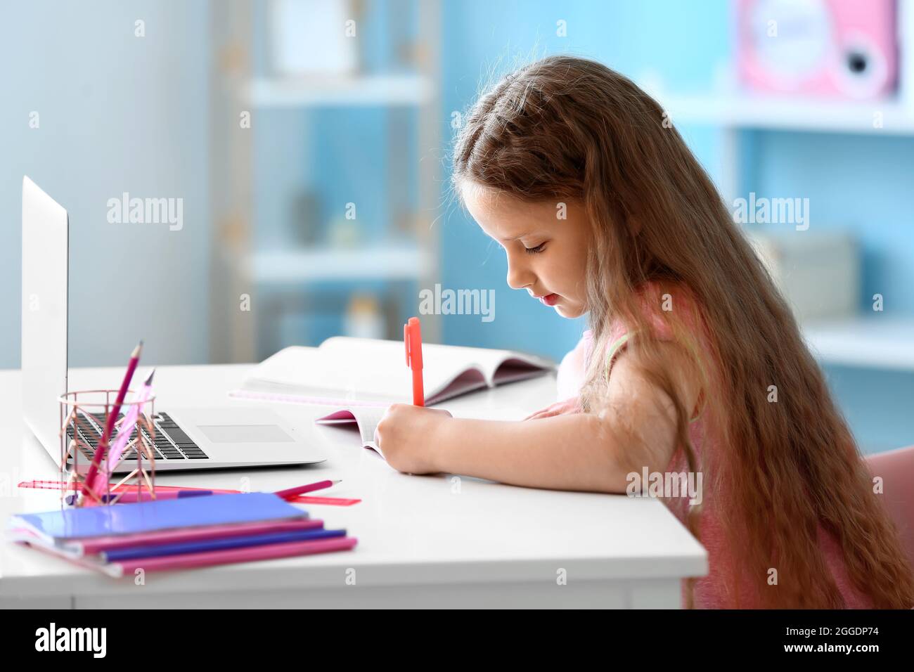 Little girl writing in notebook at home Stock Photo