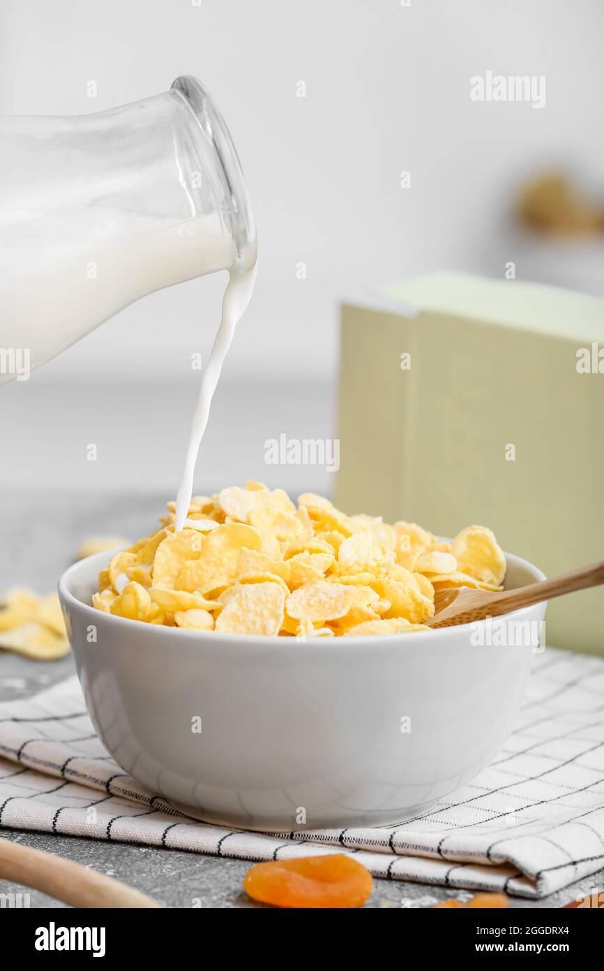 https://c8.alamy.com/comp/2GGDRX4/pouring-of-milk-from-bottle-into-bowl-with-corn-flakes-on-table-in-kitchen-2GGDRX4.jpg