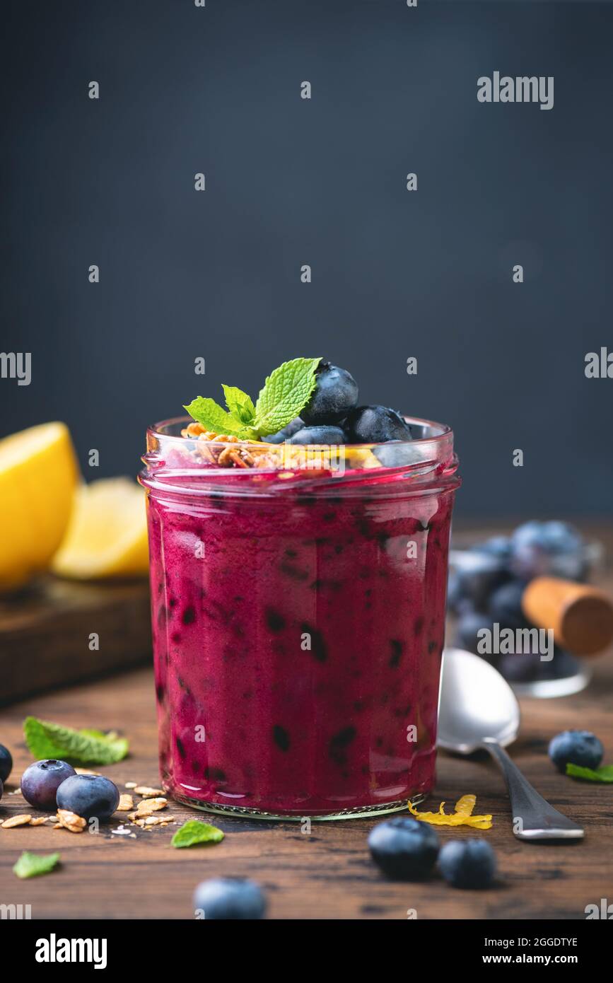 Purple blueberry smoothie in a glass jar, dark blue chalk background with copy space. Vegan superfood smoothie Stock Photo