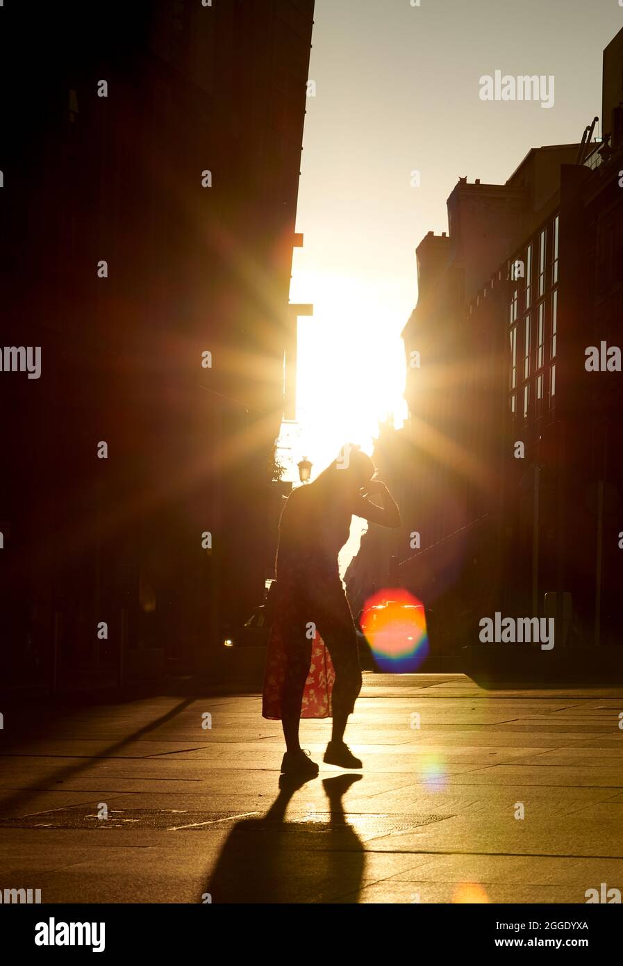 Silhouette of a lonely girl walking on a warm street facing a twilight background, suffering the effects of climate change and global warming. Stock Photo
