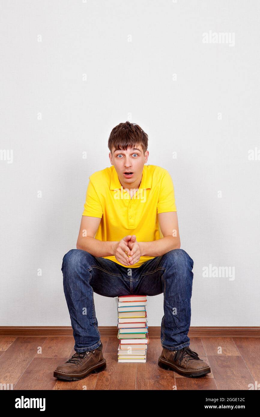 Surprised Young Man with a Books on the Floor in the Room Stock Photo