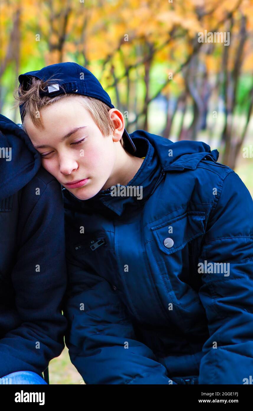 Tired Teenager sleeping on the Friend Shoulder outdoor Stock Photo