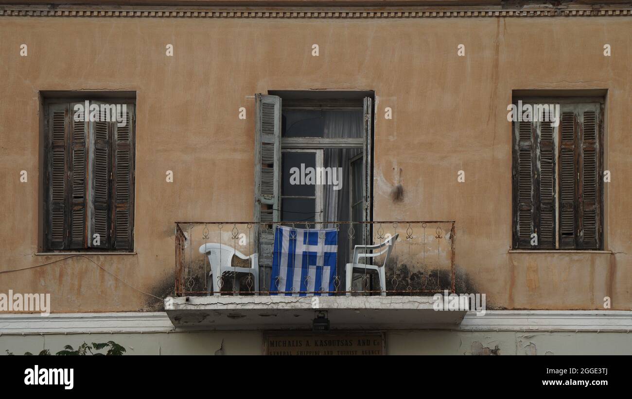 traditional old historic balcony and the Greek flag, Itea, Greece Stock Photo