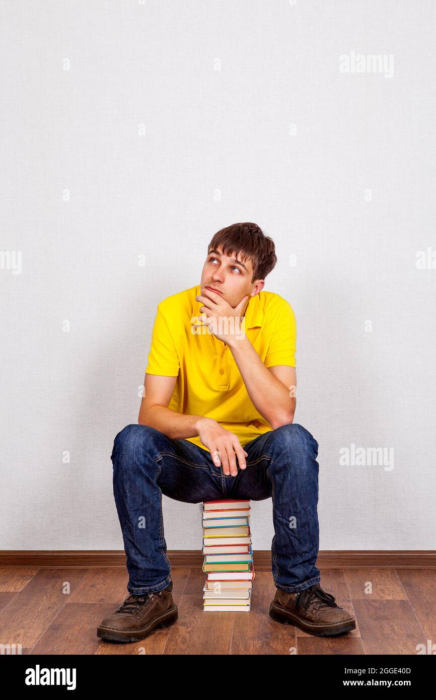 Pensive Young Man with a Books on the Floor in the Room Stock Photo