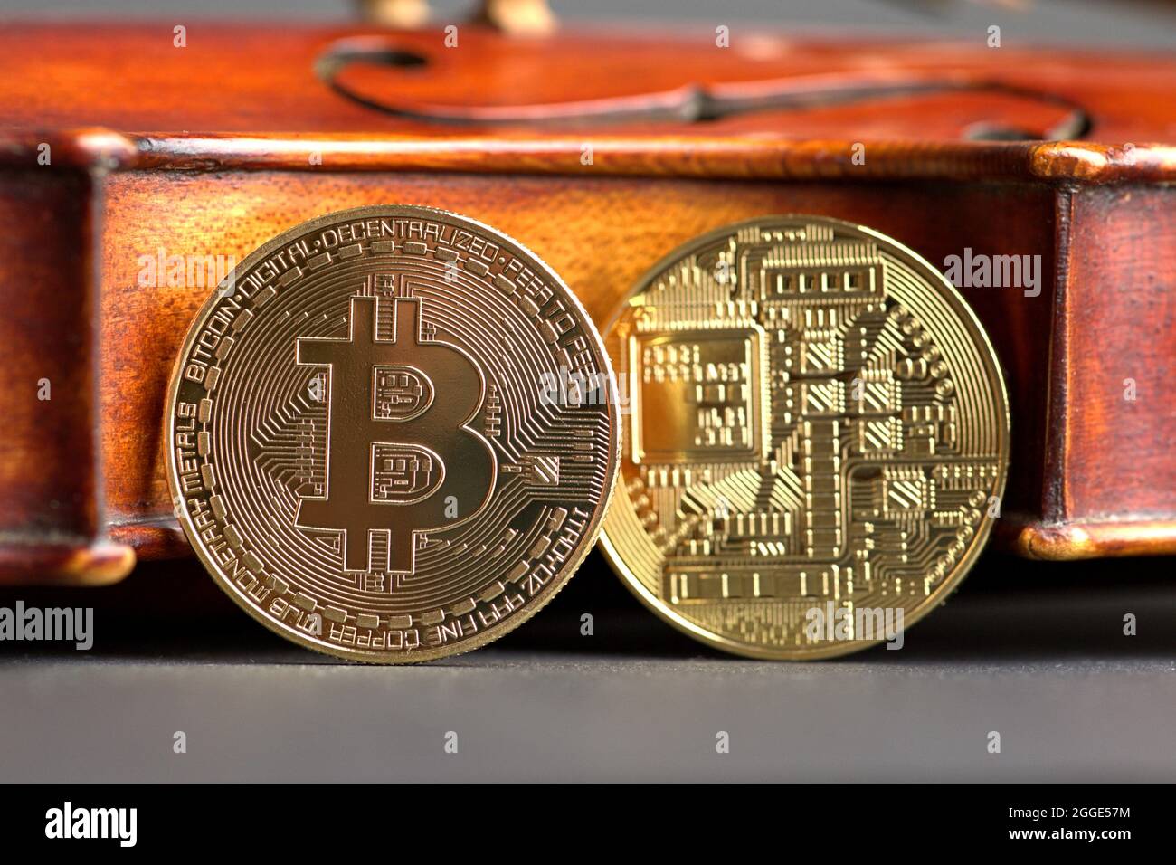 Two bitcoins as coins with front and back on the body of an old violin.  Symbolic