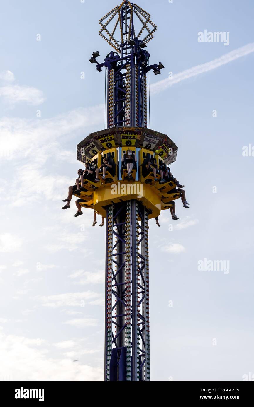 St. Thomas, Ontario, Canada - July 23 2021: People aboard the Cannon Ball fair ride at the St. Thomas Summer Carnival. Legs hanging. Stock Photo