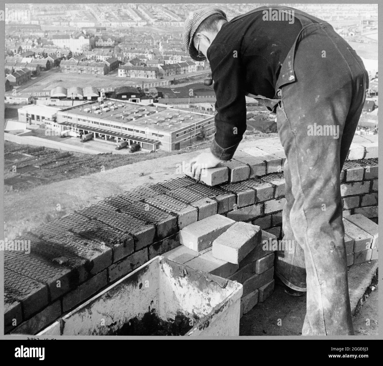 A worker laying bricks to the top of the chimney shaft during the construction of Plymouth 'B' Power Station. This image was catalogued as part of the Breaking New Ground Project in partnership with the John Laing Charitable Trust in 2019-20. Stock Photo