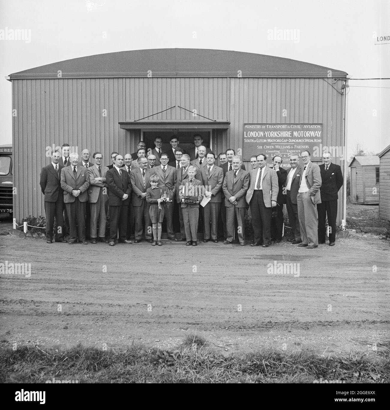 Senior staff involved in the construction of the M1, the London to Yorkshire Motorway, posed infront of the 'newsroom' at the project headquarters in Newport Pagnell, on the day the motorway completion certificate was signed. This image was catalogued as part of the Breaking New Ground Project in partnership with the John Laing Charitable Trust in 2019-20. Stock Photo