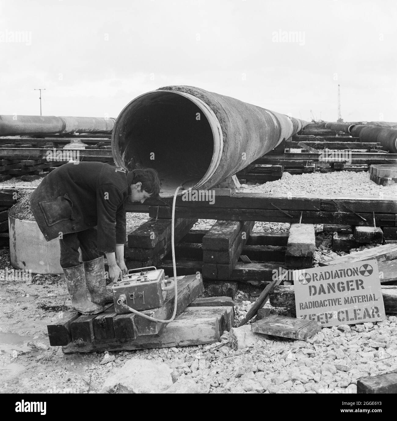 A worker carrying out an x-ray of the North Coates pipeline, checking for faults in the welding. The civil engineering work on the North Coates oil pipeline was carried out by Laing Pipelines along with French companies Entrepose and GTM. Over two miles of 36 inch diameter pipeline, encased in concrete, was later pulled out to sea in the Humber Estuary. Stock Photo