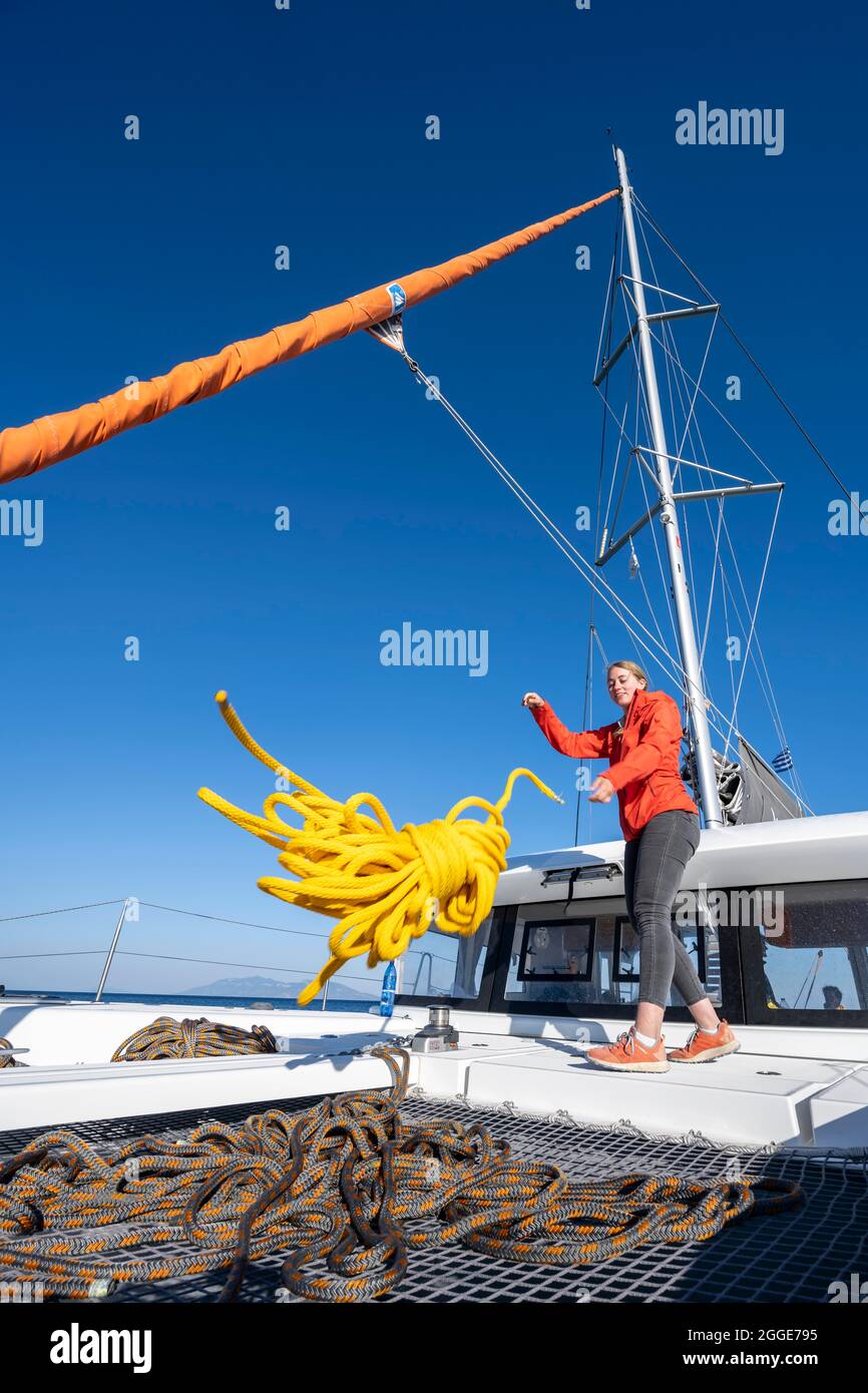 Young woman throws a rope on deck, sailing catamaran, sailing trip, Dodecanese, Greece Stock Photo