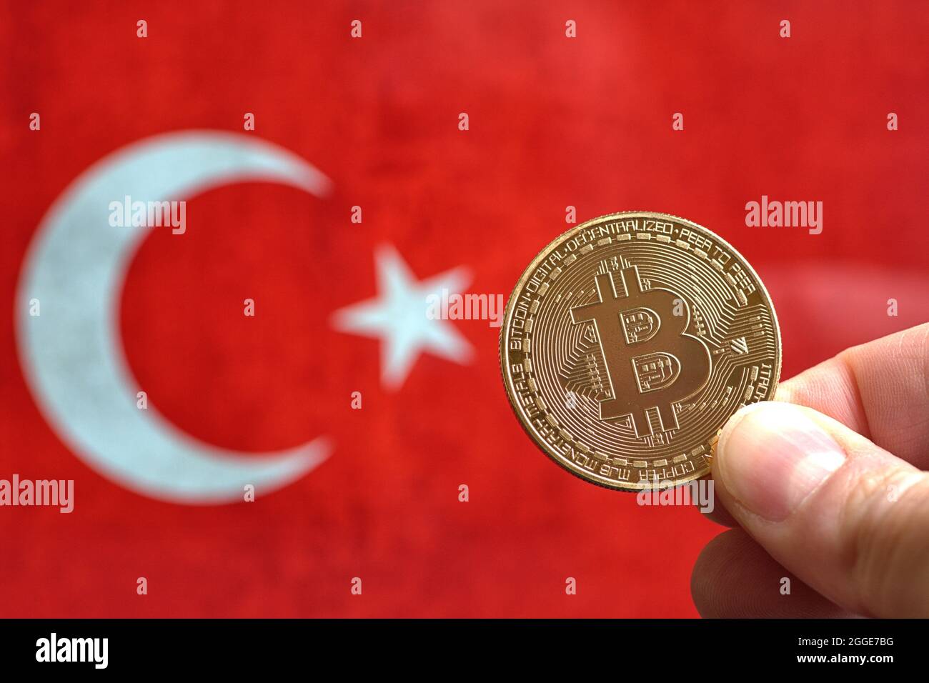 A bitcoin coin held by a hand in front of a representation of the Turkish  flag. Turkey is versus cryptocurrency and prohibits all payments with  digital currencies Stock Photo - Alamy