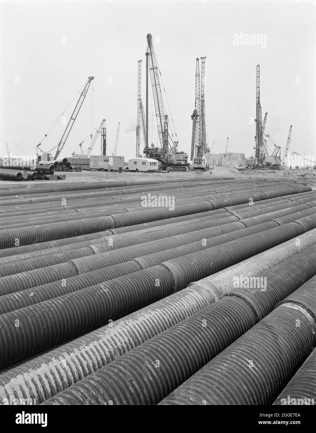 Piling in progress during the construction of the Isle of Grain Power Station, showing a stockpile of ribbed tubing laid out in the foreground. The Isle of Grain Power Station was an oil fired power station built in the 1970&#x2019;s by multiple contractors, including John Laing and Son Ltd. When the power station opened in 1979, it had the second tallest chimney in the UK at 244 metres high. The power station has now been demolished and the chimney was destroyed in September 2016. A new Combined Cycle Gas Turbine (CCGT) power station has been built at the site. Stock Photo