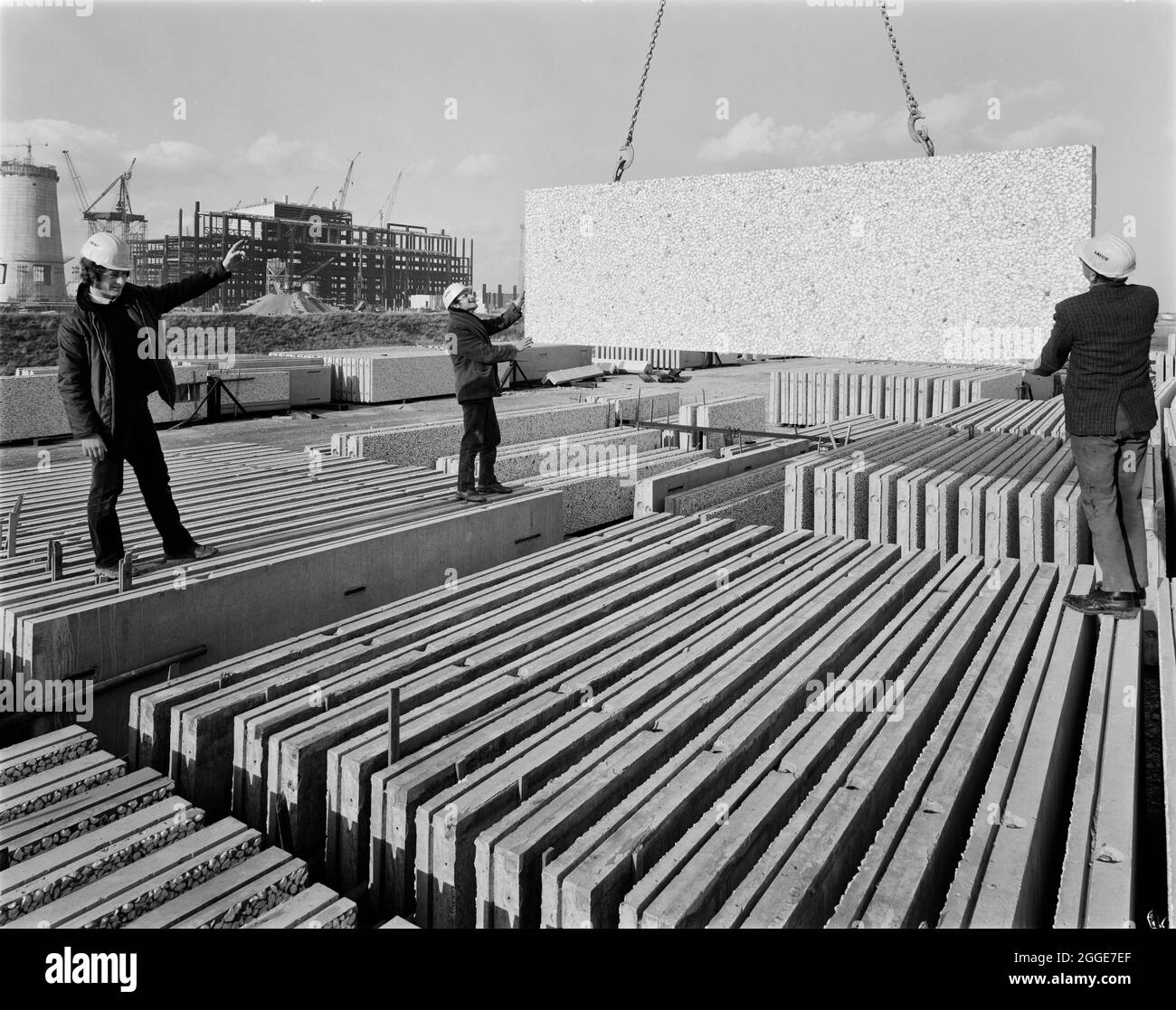 Laing workers assisting with the movement of a rectangular concrete slab at a stockpile on the construction site of the Isle of Grain Power Station. The Isle of Grain Power Station was an oil fired power station built in the 1970&#x2019;s by multiple contractors, including John Laing and Son Ltd. When the power station opened in 1979, it had the second tallest chimney in the UK at 244 metres high. The power station has now been demolished and the chimney was destroyed in September 2016. A new Combined Cycle Gas Turbine (CCGT) power station has been built at the site. Stock Photo