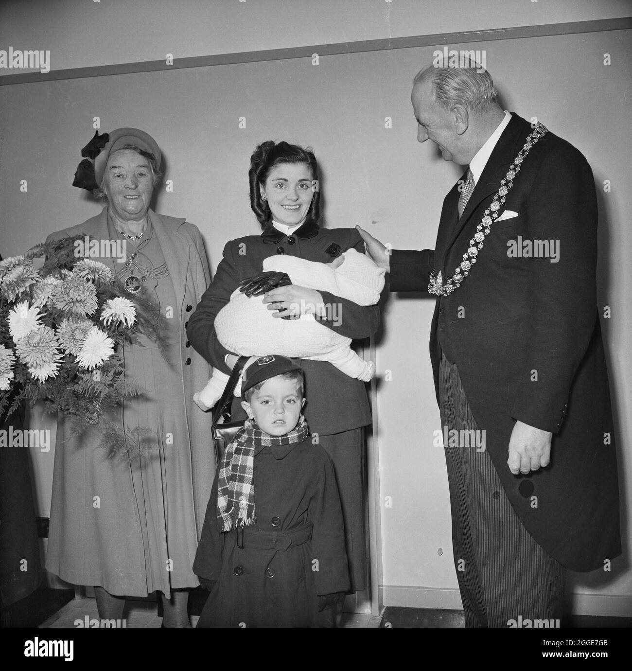 A woman and her two children, the tenants of the 3000th Easiform dwelling to be completed in Bristol, posed next to the Lord Mayor of Bristol and the Lady Mayoress. This image shows the opening of the 3000th Easiform dwelling in Bristol. The key was presented to the tenant by the Lord Mayor of Bristol. The Chairman of the Housing Committee announced that the new tenant was the 16,689th tenant to be housed or rehoused by the Council following the end of the Second World War in 1945. Sir Maurice Laing also attended the ceremony and reflected on the success of the house building programme in Bris Stock Photo