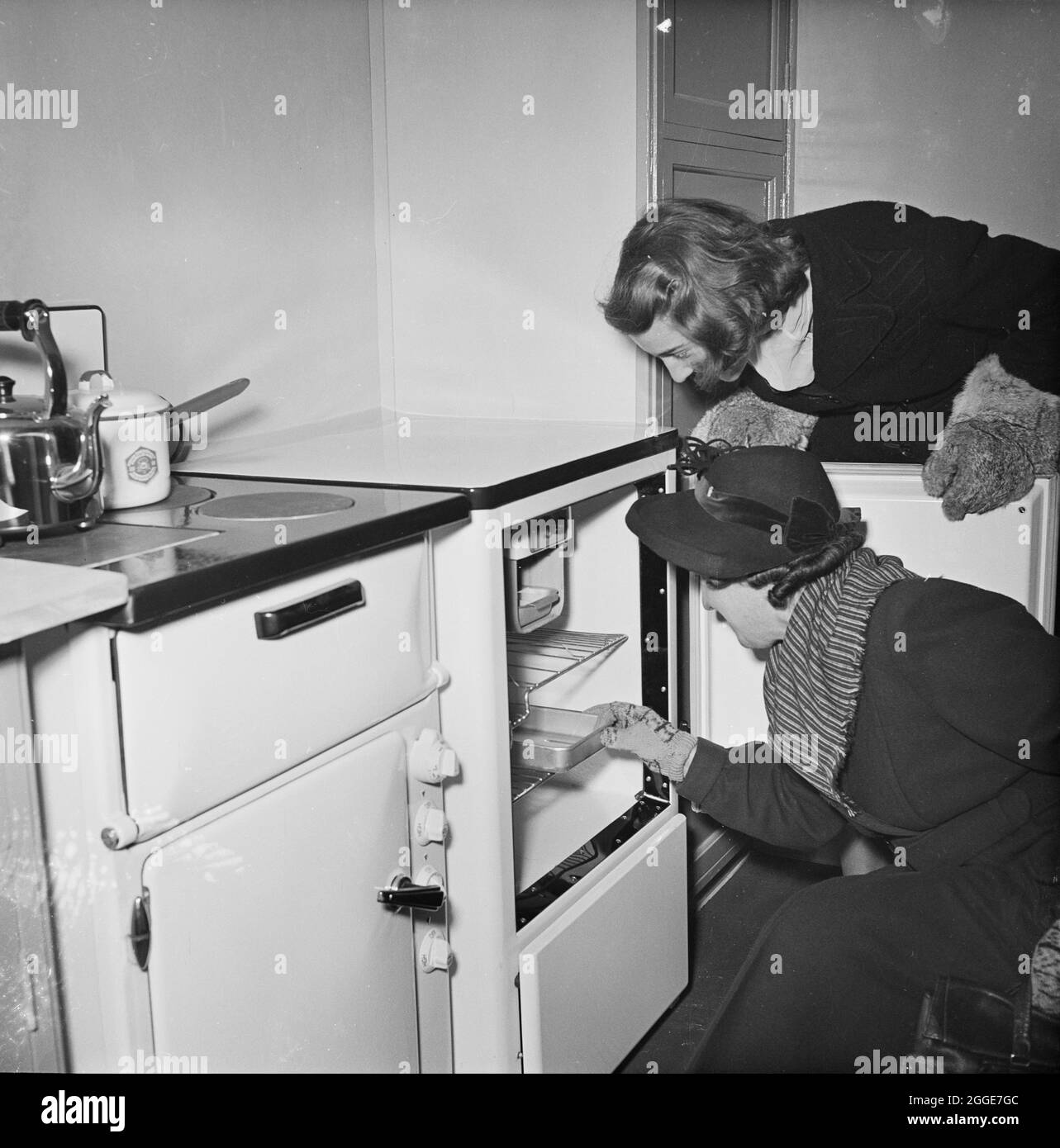 Two women admiring a fridge in the kitchen of the 3000th Easiform dwelling to be completed in Bristol, on the day of the ceremonial opening. This image is recorded in the Laing register as having been taken for the South-West Board. Stock Photo