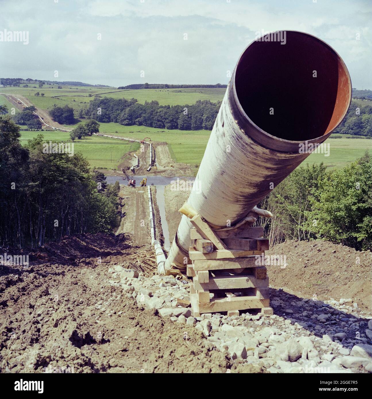 A view along the route of the Brampton pipeline, showing the pipe at a 45 degree angle in the foreground, where it meets a slope. In 1975, Laing Pipelines laid the Brampton gas pipeline between Longtown near Carlisle to the east of Bishop Auckland. The pipeline is a section of the Frigg pipeline carrying natural gas from the North Sea to near Peterhead in Scotland. The headquarters for the Laing contract was located at an old quarry near Brampton. Stock Photo