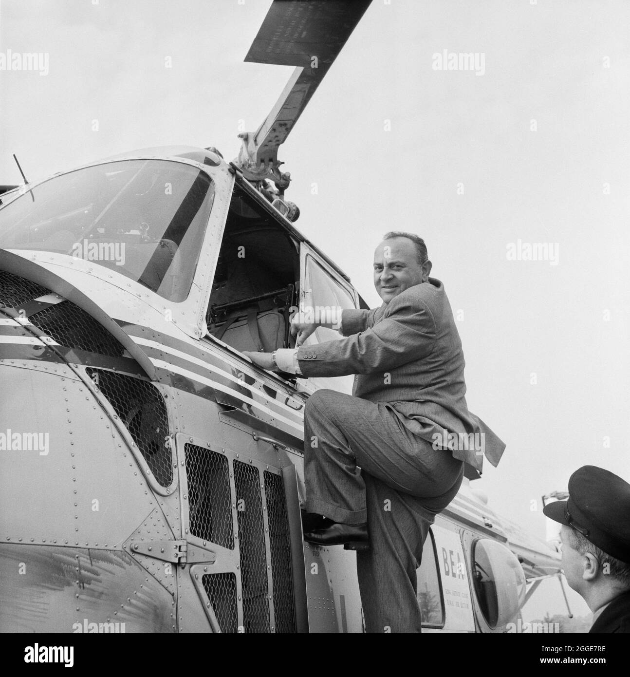 P. A. Gaglardi, the Minister of Highways for British Columbia, climbing into a helicopter for a tour of the London to Yorkshire Motorway (the M1). W. B. Haughan; President of the Company in Canada, G. S. Gibson; Deputy Agent General British Columbia House, and J. Gregg also joined P. A. Gaglardi on the helicopter tour of the motorway. Stock Photo