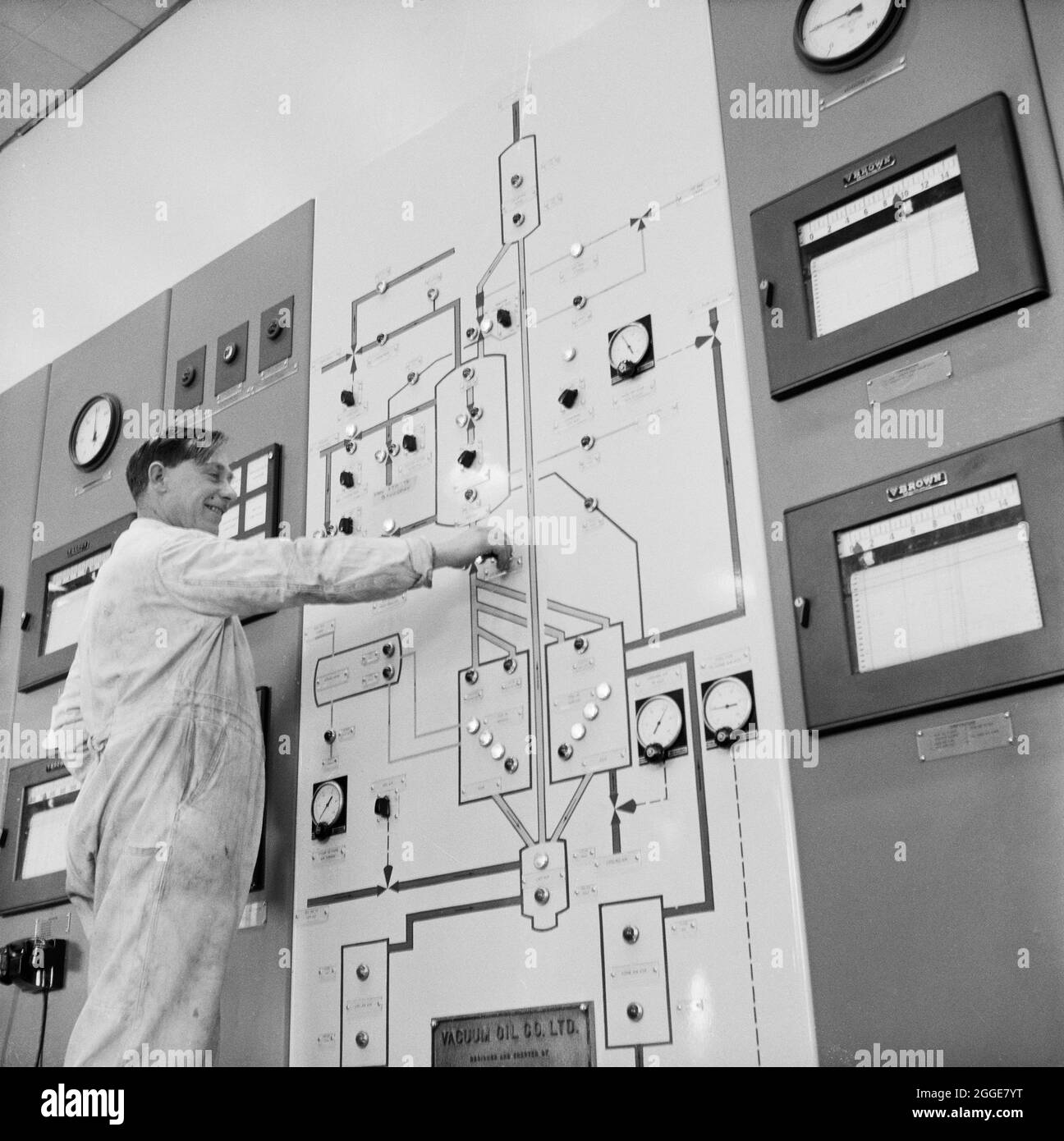A worker operating the control board in the control room of the Air-Lift Thermofor Catalytic Cracking Unit at Coryton Oil Refinery. Coryton Oil Refinery was ceremonially opened in May 1954 by Her Majesty Queen Elizabeth, the Queen Mother. It was operated by Vacuum Oil Company; a unit of Mobil. From 1996, the refinery was run by BP as part of a joint venture with Mobil. Ownership of Coryton Refinery was later transferred to BP in 2000, and then Petroplus Holdings in 2007. Major products of the refinery included petrol and diesel, aviation fuels, liquefied petroleum gas, fuel oils and bitumen. C Stock Photo
