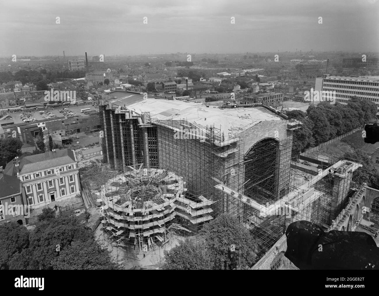 A view from the spire of the Cathedral Church of Saint Michael, looking in a north-east direction over the construction site of the new Coventry Cathedral, showing work on the roof and the construction of the Chapel of Unity on the left of the foreground. Construction of the new cathedral took place between the mid-1950s and 1962 with the foundation laying ceremony being carried out by Queen Elizabeth II on 23 March 1956. This photograph was taken to show the progress of the construction. Stock Photo