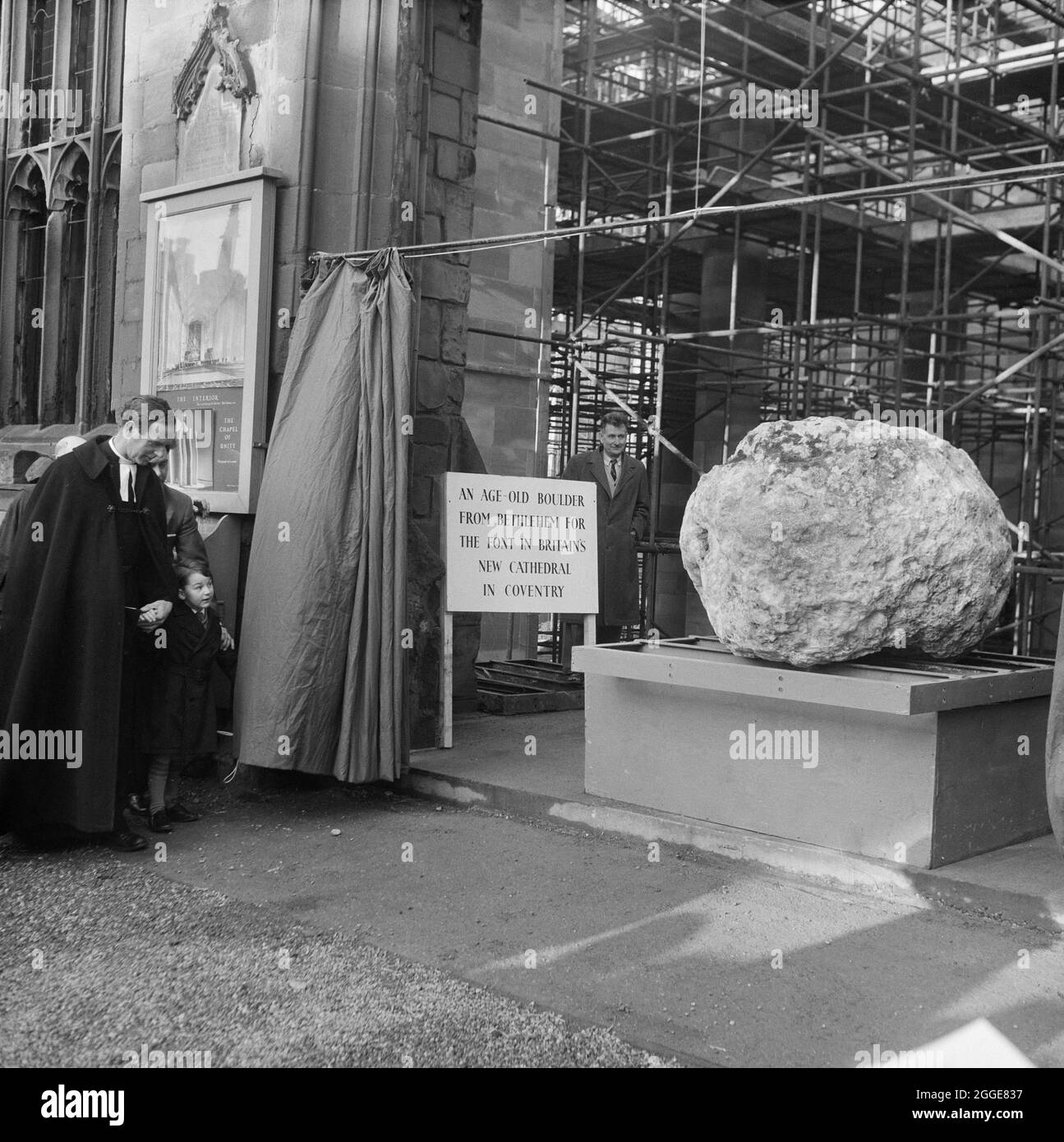 The Provost of Coventry Cathedral with Henry Sumner at the unveiling ceremony of the Boulder from Bethlehem. The boulder which was brought from a hillside in Bethlehem was transported to Coventry Cathedral to be used as its new font. Weighing three tons, it was transported to Manchester Docks in the SS Norman Prince and then on to Coventry. The unveiling ceremony took place on 22nd December 1960 and the boulder was unveiled by 7-year-old Henry Sumner, son of the foreman carpenter at Coventry Cathedral. The boulder was later moved to its current position in front of the baptistery window. Stock Photo