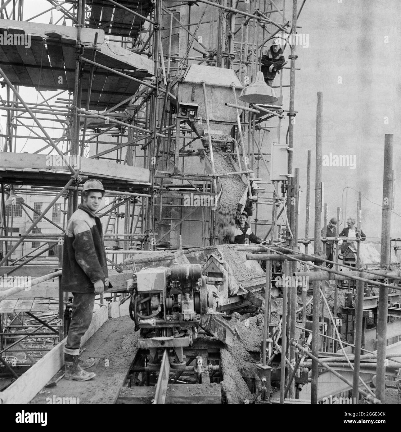 A view from scaffolding during the construction of a sugar silo at the Allscott Sugar Beet Factory, showing some of the team working on the site and concrete being poured from a hopper. A sugar beet factory was at Allscott from 1927 until it closed in 2007. Laing built two sugar silos here in 1961 for the British Sugar Corporation who were the owners of the site. Each silo was able to store 10,000 tons of granulated sugar and at the time they were constructed, they were the tallest that Laing had built so far using sliding formwork. Stock Photo