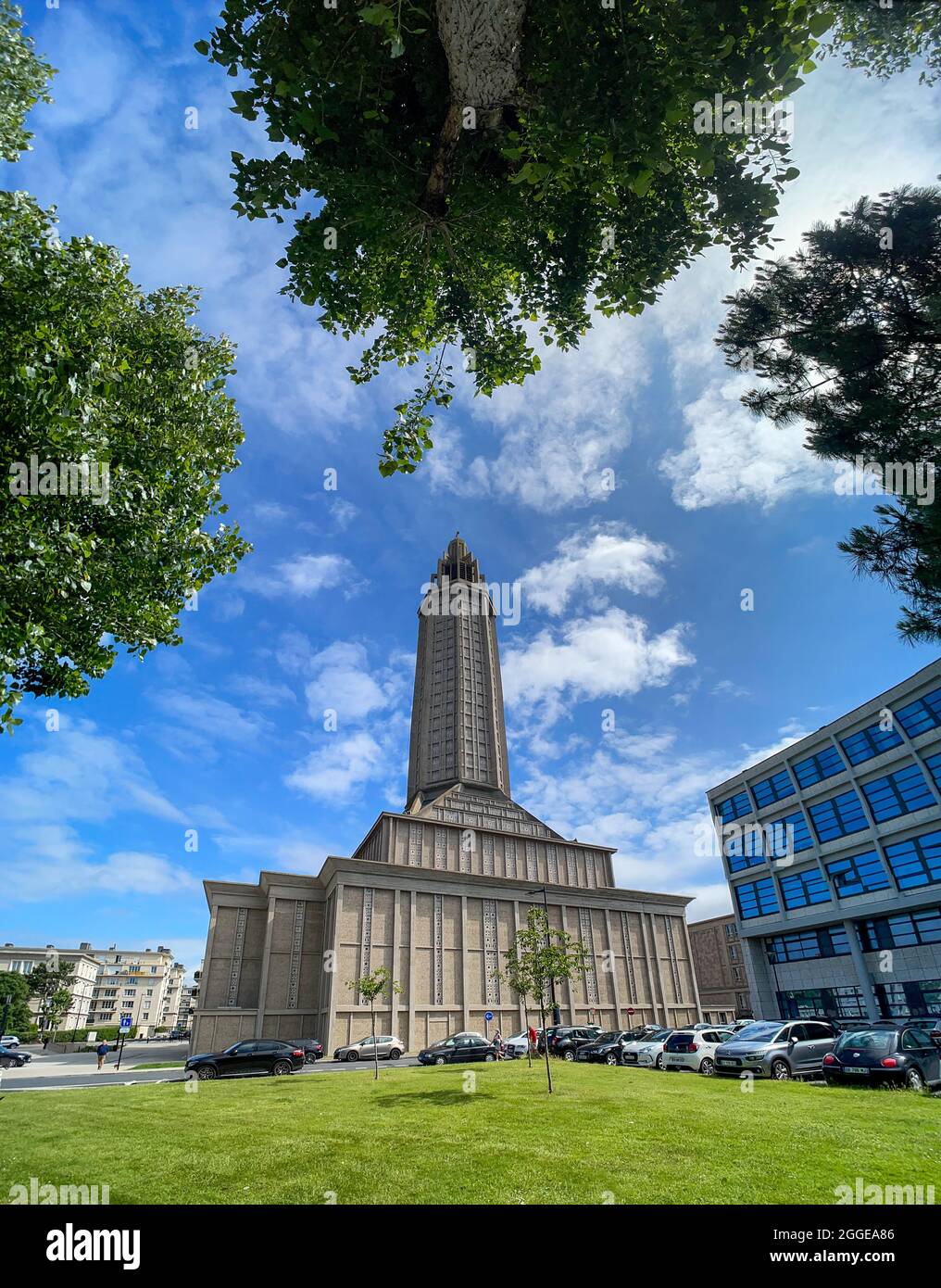 Wide-angle shot of St Joseph's Church with blue sky and framed by trees in Le Havre, Seine-Maritime department, France Stock Photo