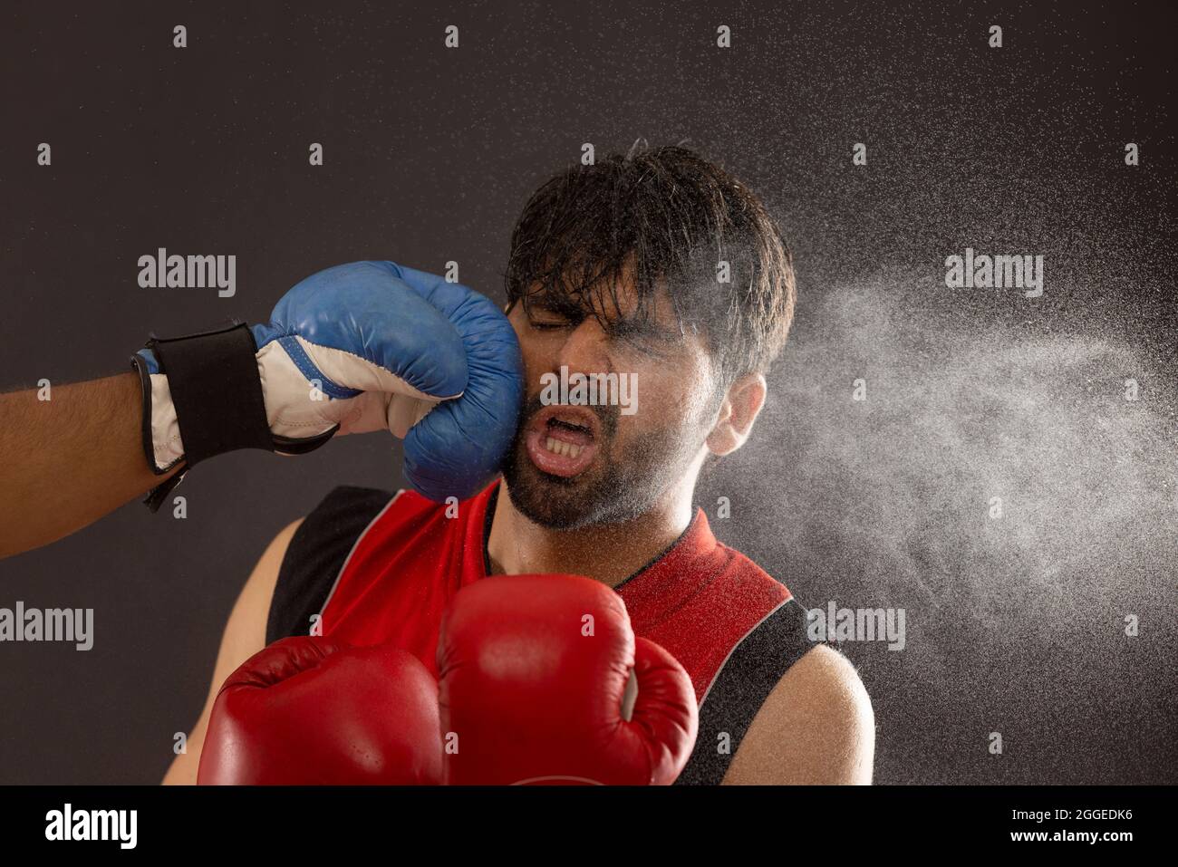 A BOXER BEING PUNCHED ON FACE BY ANOTHER PLAYER WHILE BOXING Stock Photo