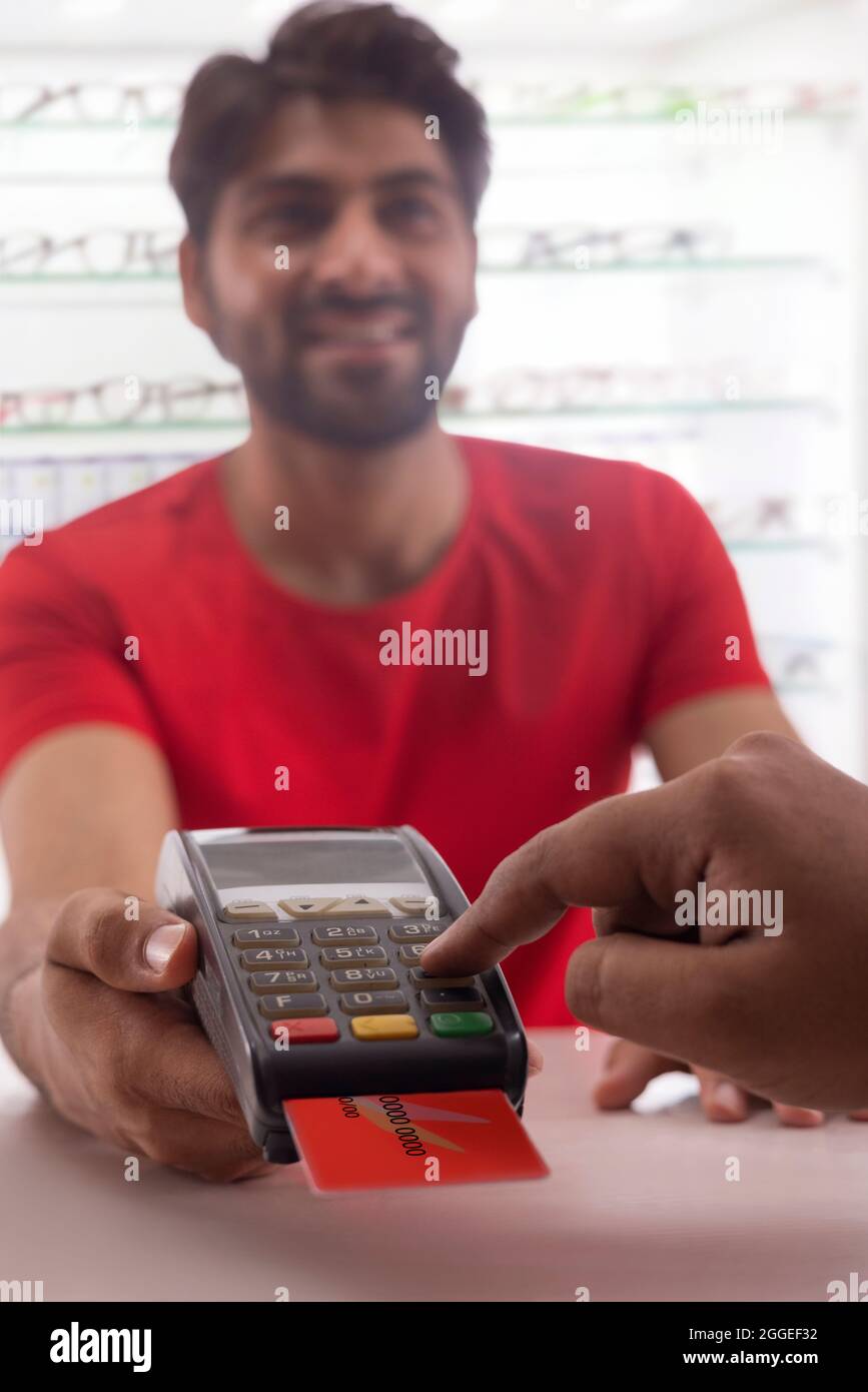 A HAPPY YOUNG MAN HOLDING CARD MACHINE FOR CUSTOMER TO PAY BILL Stock ...